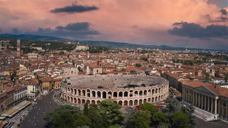 Rimski amfiteater je obdan z mestno arhitekturo in strešnimi kritinami ter pod oblačnim nebom.
